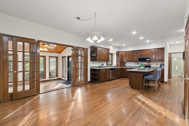 kitchen featuring a center island, hardwood / wood-style floors, decorative light fixtures, a breakfast bar area, and appliances with stainless steel finishes