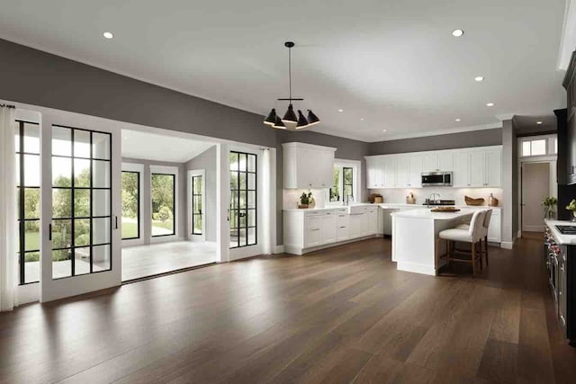 kitchen featuring a breakfast bar, dark wood-type flooring, white cabinets, hanging light fixtures, and a kitchen island