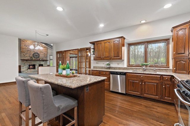 kitchen with stainless steel appliances, sink, a center island, a stone fireplace, and a breakfast bar area