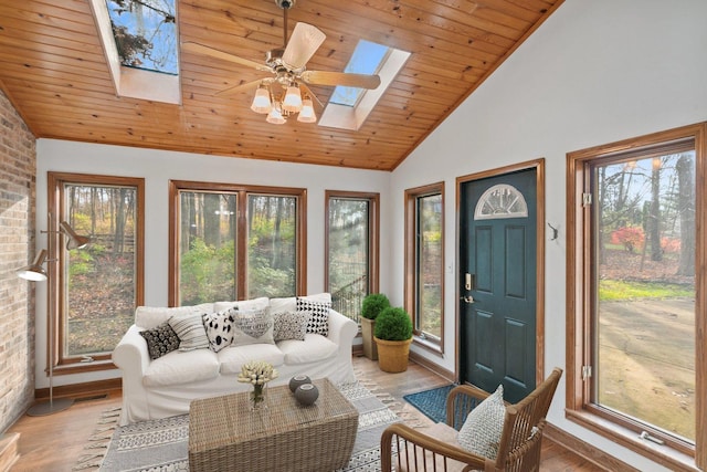 sunroom / solarium featuring vaulted ceiling with skylight, plenty of natural light, ceiling fan, and wood ceiling