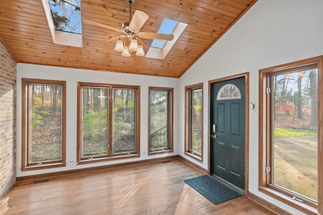 foyer entrance with wood ceiling, lofted ceiling with skylight, ceiling fan, a healthy amount of sunlight, and hardwood / wood-style flooring