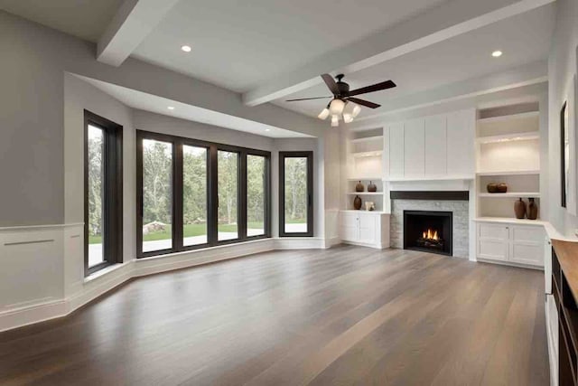 unfurnished living room featuring built in shelves, ceiling fan, beamed ceiling, and hardwood / wood-style flooring