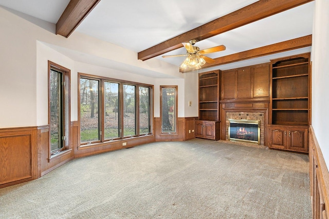 unfurnished living room with beam ceiling, light colored carpet, and ceiling fan