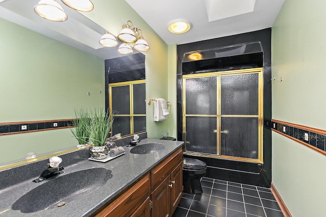 full bathroom featuring combined bath / shower with glass door, a skylight, vanity, tile patterned flooring, and toilet