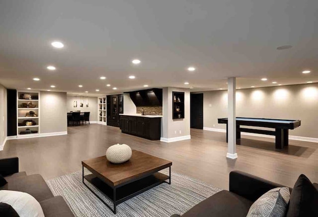 living room with built in shelves, light hardwood / wood-style flooring, bar, and pool table