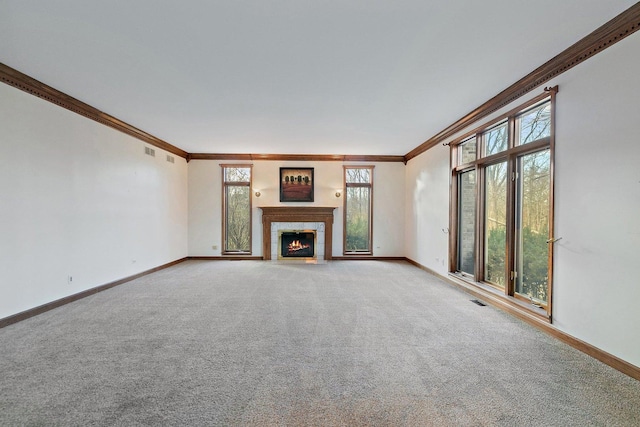 unfurnished living room featuring carpet, a healthy amount of sunlight, and ornamental molding