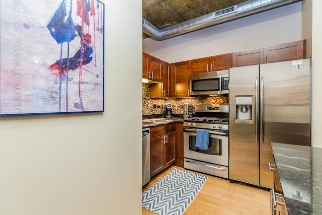 kitchen featuring tasteful backsplash, sink, light hardwood / wood-style floors, and appliances with stainless steel finishes