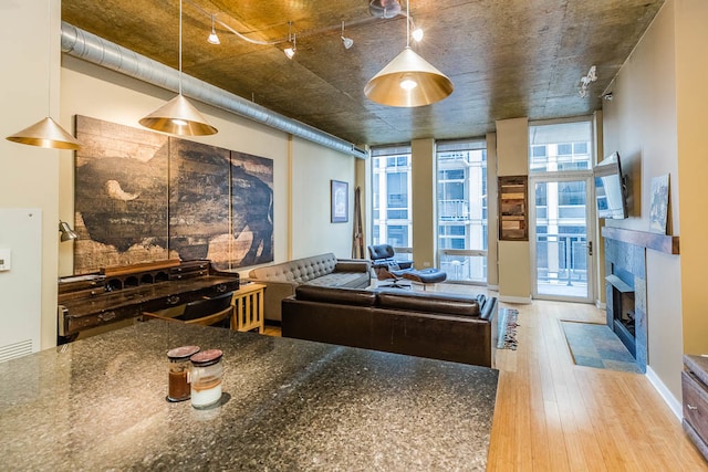 kitchen with dark stone countertops, hanging light fixtures, and hardwood / wood-style flooring