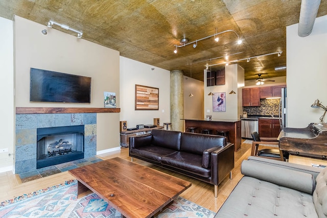 living room with a fireplace, light wood-type flooring, and ceiling fan