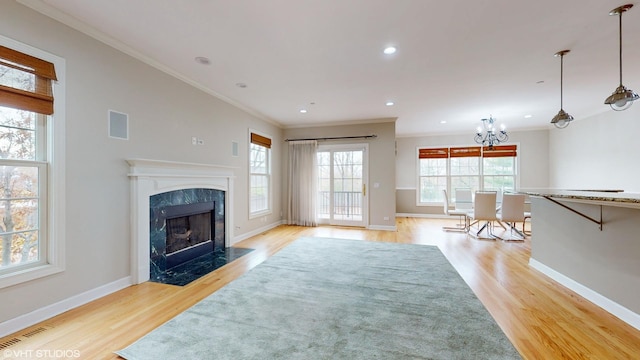 living room featuring a fireplace, light wood-type flooring, plenty of natural light, and ornamental molding