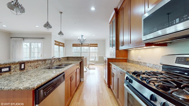 kitchen with appliances with stainless steel finishes, light hardwood / wood-style flooring, a wealth of natural light, and sink