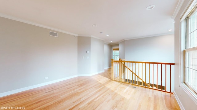 spare room with ornamental molding, a healthy amount of sunlight, and light hardwood / wood-style floors