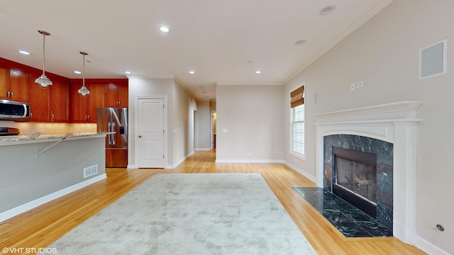 living room with light hardwood / wood-style floors, crown molding, and a fireplace