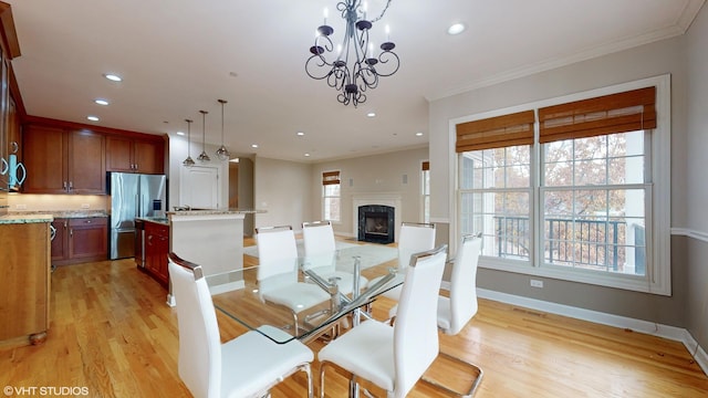 dining area featuring a notable chandelier, light hardwood / wood-style floors, and ornamental molding