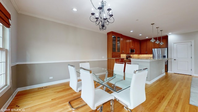 unfurnished dining area with a chandelier, light hardwood / wood-style floors, and crown molding