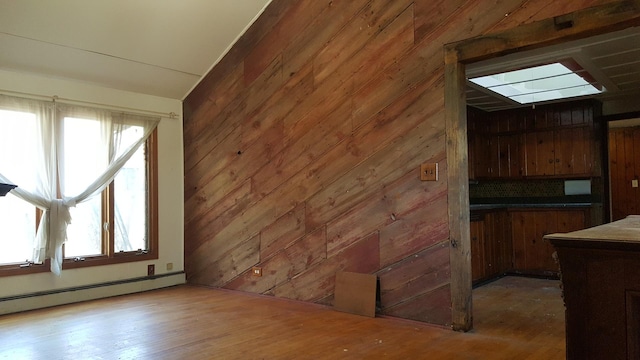 interior space featuring wood walls, a baseboard heating unit, and wood finished floors