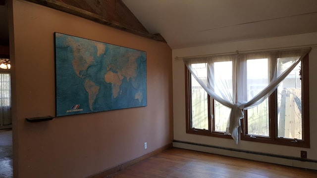 spare room featuring a baseboard heating unit, wood finished floors, lofted ceiling, and baseboards