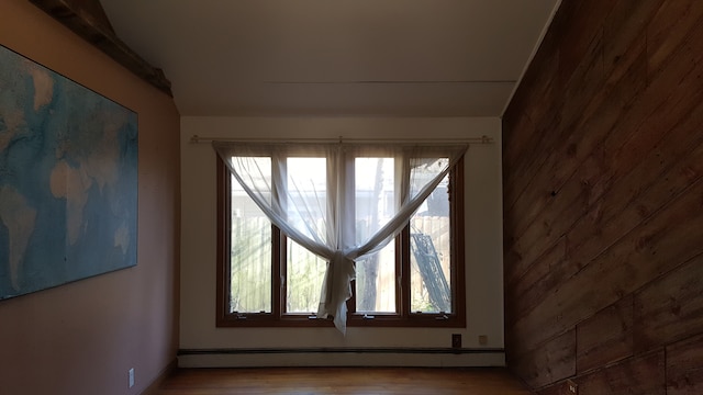 interior space with hardwood / wood-style flooring, baseboard heating, and wooden walls