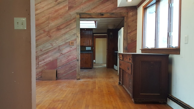 hall with light hardwood / wood-style flooring and wood walls