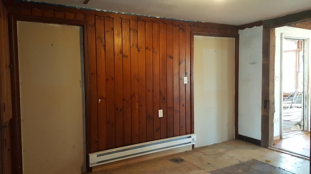 empty room featuring wood walls and a baseboard radiator