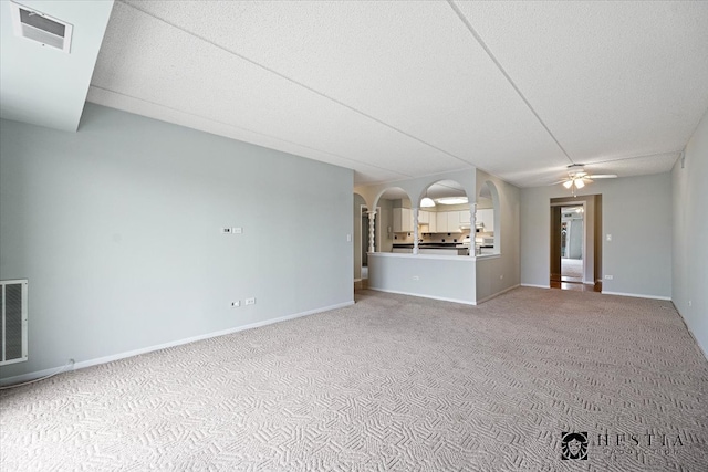 unfurnished living room featuring carpet flooring, ceiling fan, and a textured ceiling