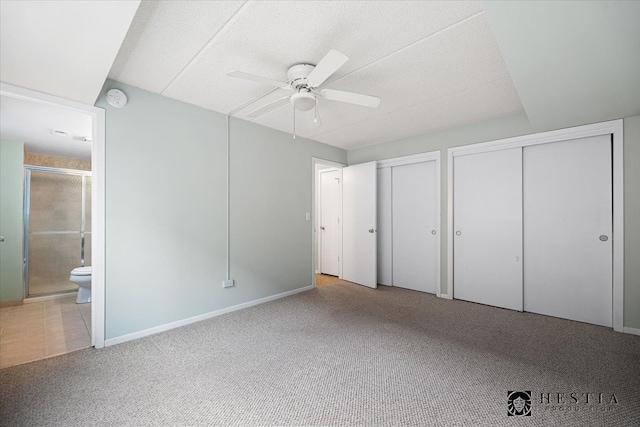 unfurnished bedroom featuring ensuite bathroom, ceiling fan, multiple closets, and light colored carpet