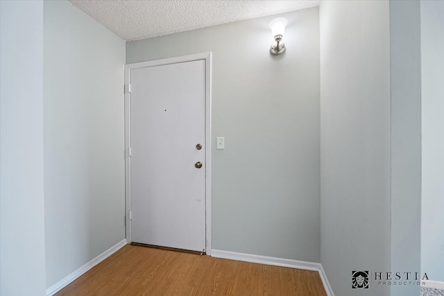 doorway to outside featuring a textured ceiling and light wood-type flooring