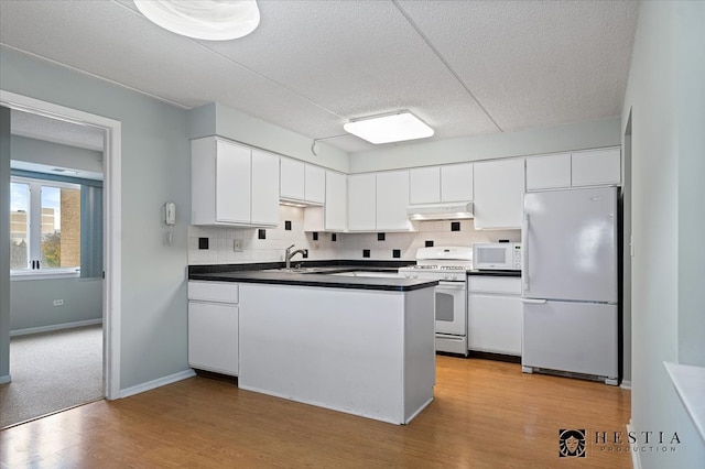 kitchen with white appliances, a textured ceiling, tasteful backsplash, light hardwood / wood-style floors, and white cabinetry