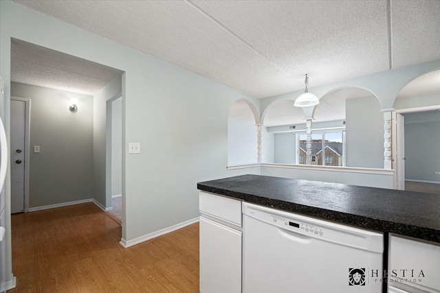 kitchen featuring white cabinetry, hardwood / wood-style floors, white dishwasher, pendant lighting, and a textured ceiling