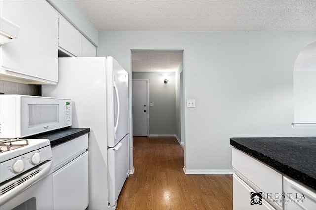 kitchen featuring white cabinets, white appliances, dark wood-type flooring, and a textured ceiling