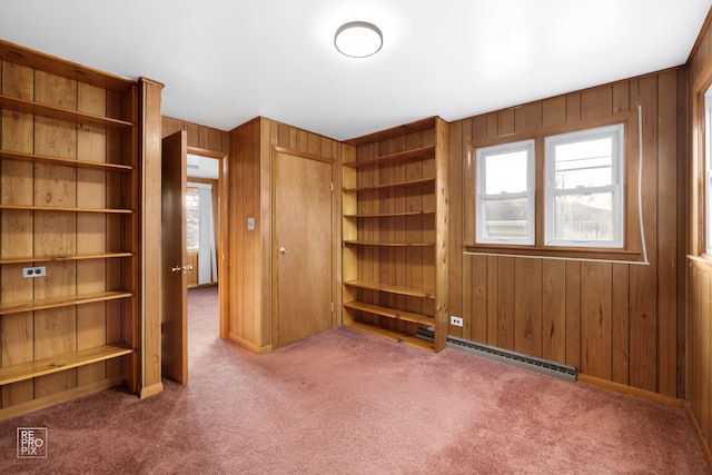 unfurnished bedroom featuring dark carpet, baseboard heating, and wooden walls