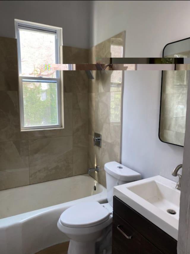 full bathroom with vanity, tiled shower / bath combo, and toilet