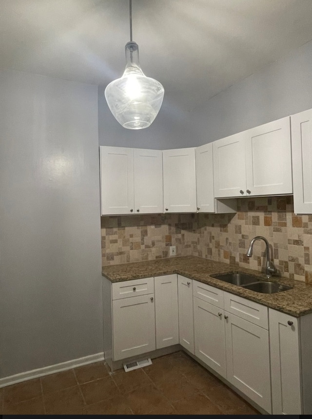 kitchen featuring decorative backsplash, sink, decorative light fixtures, dark stone countertops, and white cabinets