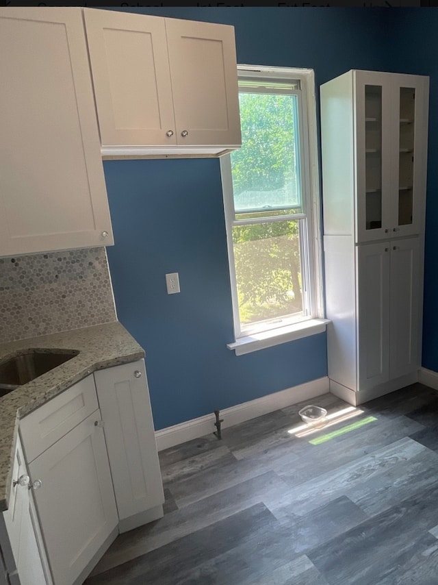 kitchen with sink, light stone counters, backsplash, white cabinets, and hardwood / wood-style flooring