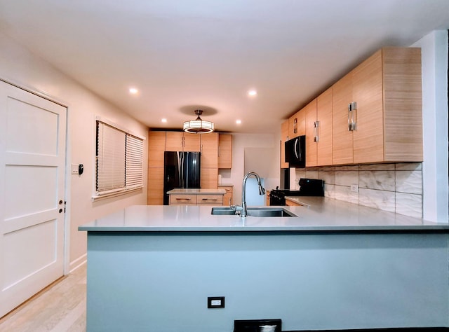 kitchen featuring sink, kitchen peninsula, decorative backsplash, light brown cabinetry, and black appliances