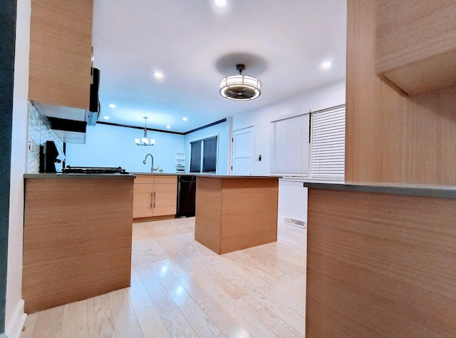 kitchen featuring kitchen peninsula, sink, decorative light fixtures, light hardwood / wood-style floors, and a kitchen island