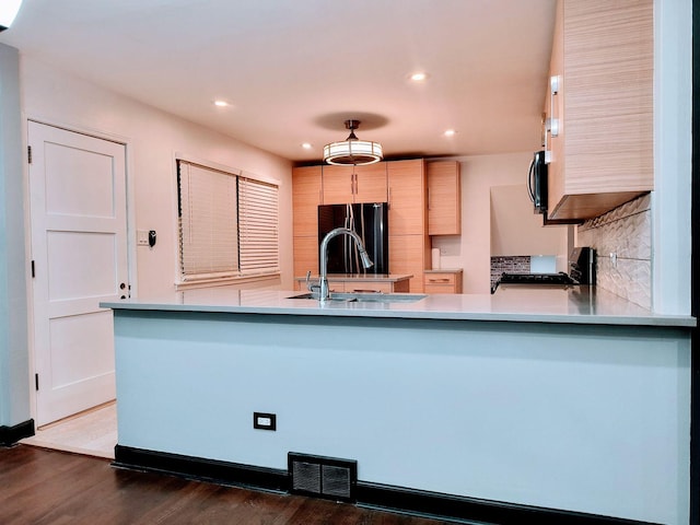 kitchen featuring black appliances, sink, light brown cabinetry, dark hardwood / wood-style flooring, and kitchen peninsula