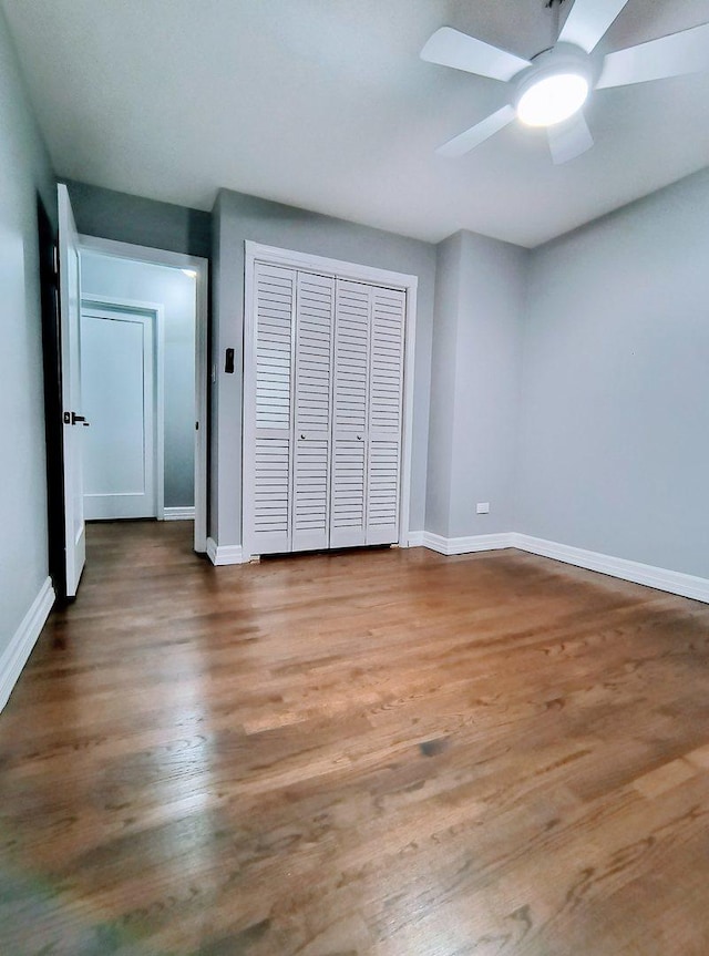 unfurnished bedroom featuring ceiling fan, a closet, and wood-type flooring