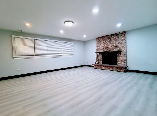 unfurnished living room with light hardwood / wood-style flooring and a brick fireplace