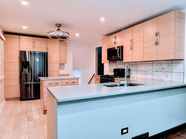 kitchen featuring sink, refrigerator with ice dispenser, kitchen peninsula, black range with gas cooktop, and light wood-type flooring