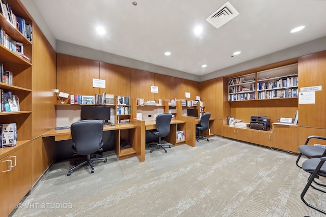 office featuring built in desk, light colored carpet, and wooden walls