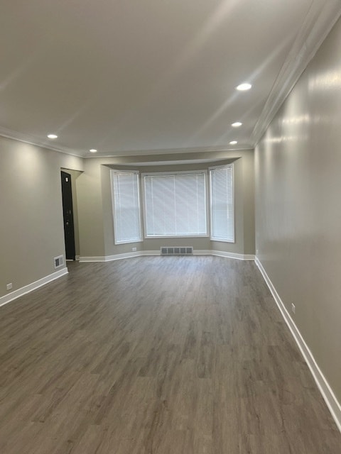 spare room featuring crown molding and dark wood-type flooring