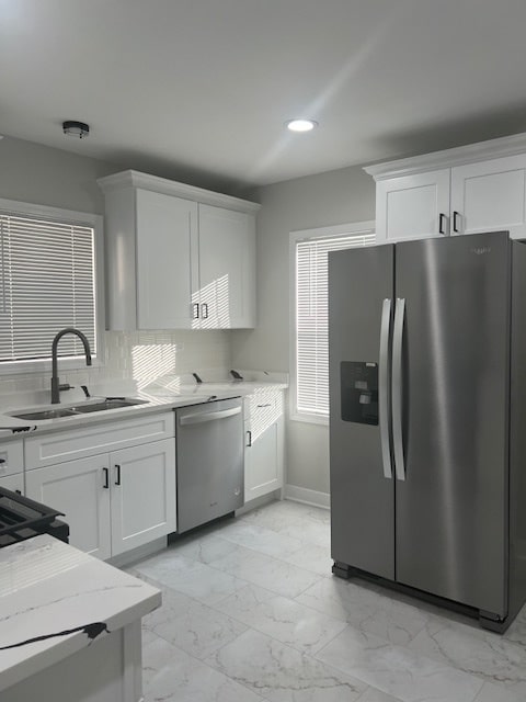 kitchen with decorative backsplash, sink, white cabinets, and stainless steel appliances