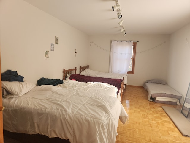 bedroom with light parquet flooring and track lighting