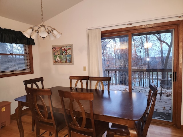 dining space featuring a chandelier, wood-type flooring, and vaulted ceiling