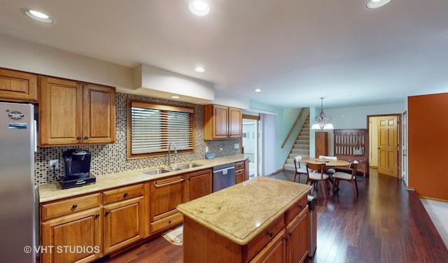 kitchen featuring sink, a center island, dark wood-type flooring, decorative light fixtures, and appliances with stainless steel finishes