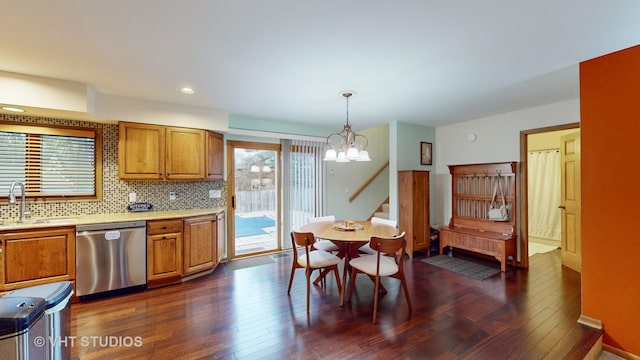 kitchen featuring dark hardwood / wood-style flooring, tasteful backsplash, sink, dishwasher, and hanging light fixtures