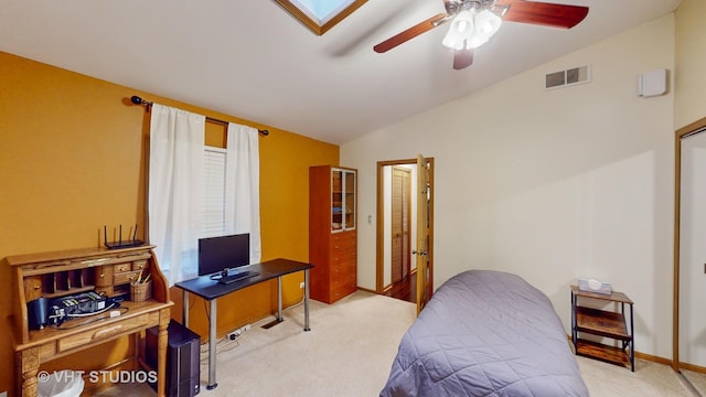 bedroom with light colored carpet, ceiling fan, and vaulted ceiling with skylight