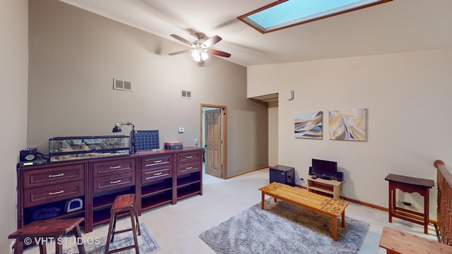 carpeted home office with ceiling fan, high vaulted ceiling, and a skylight