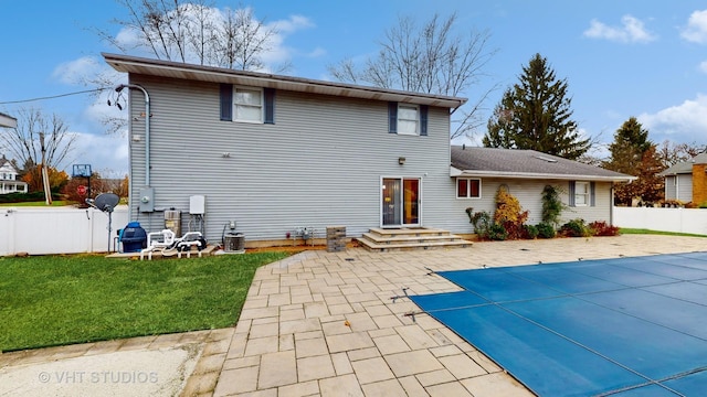 rear view of house featuring a patio area, a yard, and a covered pool